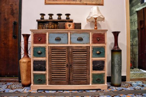 a wooden cabinet with drawers and a lamp and vases at Mumian inn in Chaozhou
