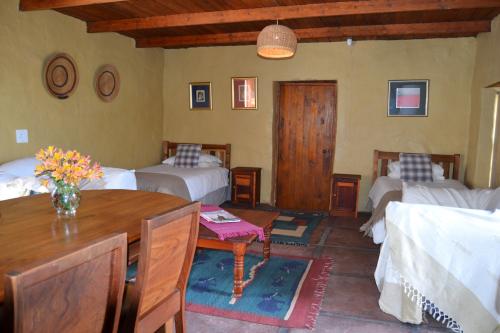 a bedroom with two beds and a table and chairs at Over The Mountain Guest Farm in George