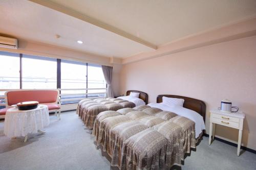 eine Reihe von Betten in einem Zimmer mit Fenstern in der Unterkunft Kochi Prince Hotel in Kōchi