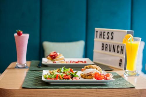 a table with two plates of food and a drink at Mandrino Hotel in Thessaloniki