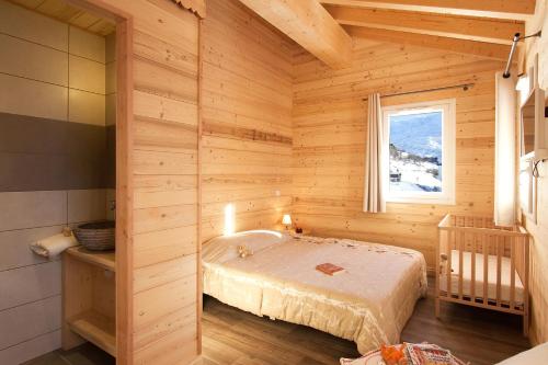 ein Schlafzimmer mit einem Bett in einem Holzzimmer in der Unterkunft Odalys Chalet De Sophie in Les Menuires