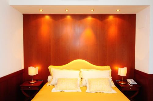 a bedroom with a yellow bed with a wooden wall at BV Grand Hotel Assisi in Assisi