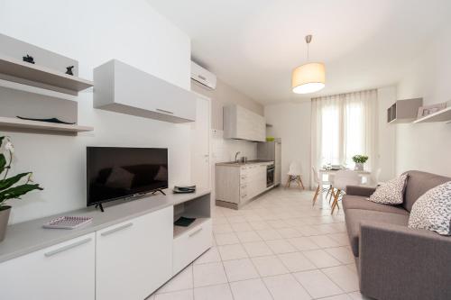 a white living room with a couch and a television at Luccainn in Lucca