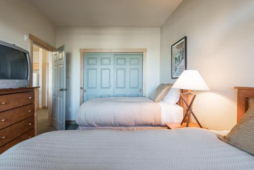 a bedroom with two beds and a tv and a door at Sunstone 325 in Old Mammoth