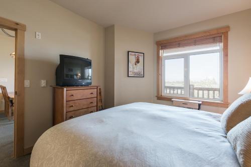 a bedroom with a bed and a tv and a window at Sunstone 325 in Old Mammoth