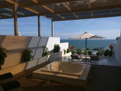 a large bath tub on a patio with an umbrella at The Cliff Residence in Mui Ne