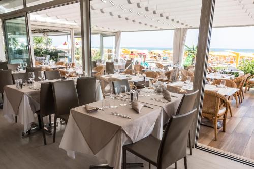 a dining room with tables and chairs and windows at Hotel Villa Sorriso in Lido di Jesolo