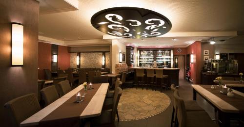 a restaurant with wooden tables and chairs and a chandelier at M13 Hotel in Riol