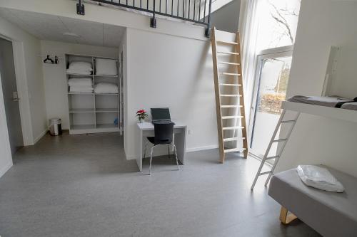 Habitación con cama elevada y escritorio con ordenador portátil. en Hostel Brønderslev, en Brønderslev