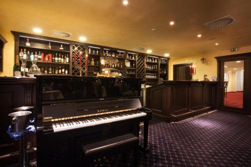 a piano in a room with a bar with alcohol at Best Western Hotel Vista in Ostrava