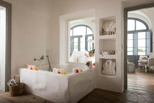 a white bathroom with a tub with a mirror at Masseria Le Torri in Polignano a Mare