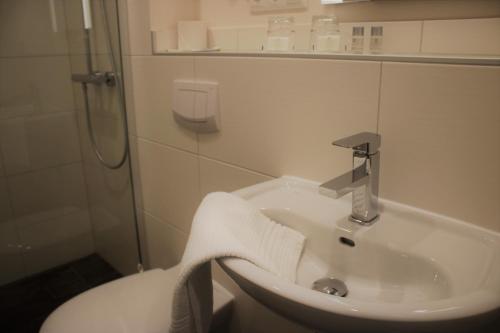 a white bathroom with a sink and a shower at Hotel-Restaurant Tüxen in Rendsburg