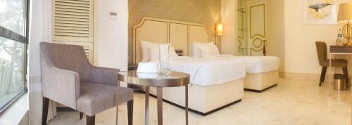 a bedroom with a bed and a table and a chair at Hotel Harbour View Colaba in Mumbai
