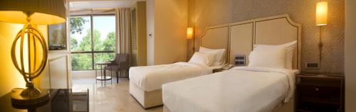a hotel room with two beds and a window at Hotel Harbour View Colaba in Mumbai