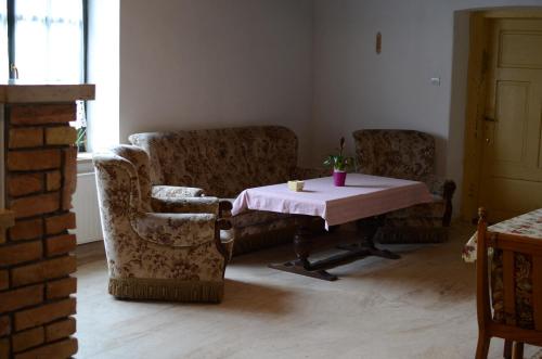 a living room with two chairs and a table with a pink tablecloth at Gerecse Vendégház in Süttő