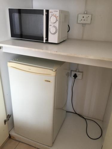 a microwave sitting on a counter next to a refrigerator at Tropical Paradise Guest House in Nelspruit
