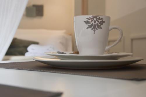 a coffee cup sitting on a table with two plates at BED IN BO Porta San Mamolo in Bologna