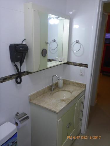 un baño con lavabo y espejo en Apartamento Capão Novo, en Capão da Canoa