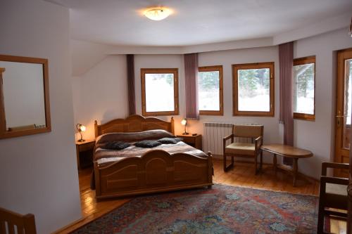 a bedroom with a bed and a chair and windows at Pensiunea Casa Elvira in Vama