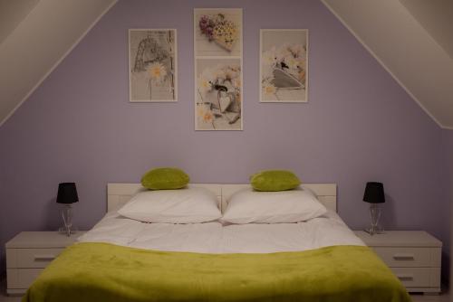 a bedroom with a bed with green sheets and pictures on the wall at Dom pod lawendowym polem in Wolibórz