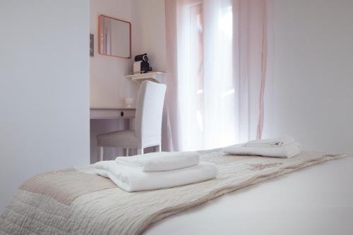 a white bedroom with a bed with towels on it at BED IN BO Porta San Mamolo in Bologna
