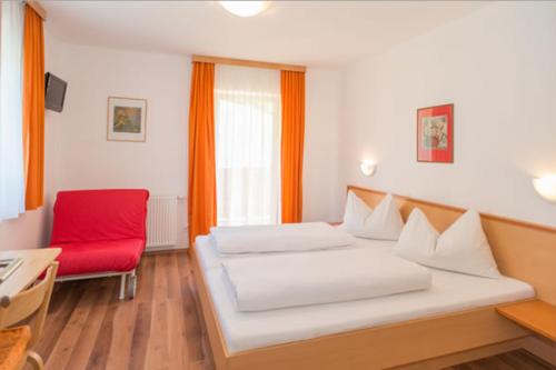 1 dormitorio con 1 cama y 1 silla roja en Haus Annemarie, en Wagrain