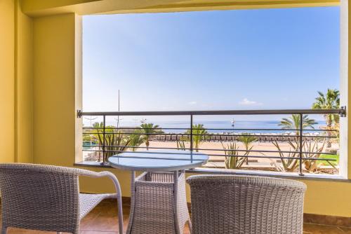 a balcony with a table and chairs and a view of the beach at Calheta Beach - All-inclusive - Savoy Signature in Calheta
