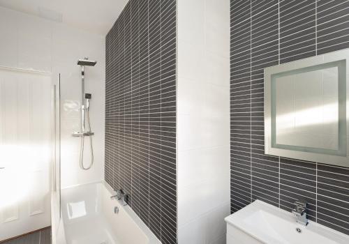 ein Badezimmer mit einer Badewanne, einem Waschbecken und einem Spiegel in der Unterkunft The Brunswick Street Residence in Edinburgh