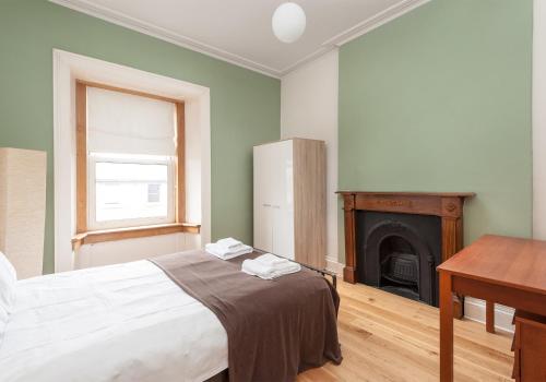 um quarto com uma cama, uma secretária e uma lareira em The Lothian Road Residence em Edimburgo