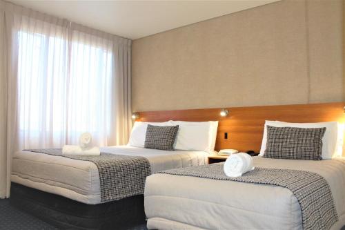 a hotel room with two beds with white sheets at Ventura Inn & Suites Hamilton in Hamilton