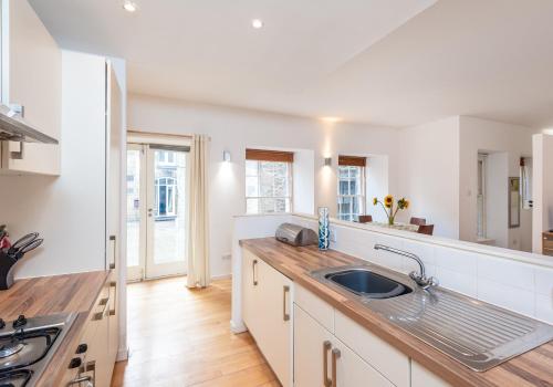 uma cozinha com armários brancos e um lavatório em The Edmonstone's Close Residence em Edimburgo