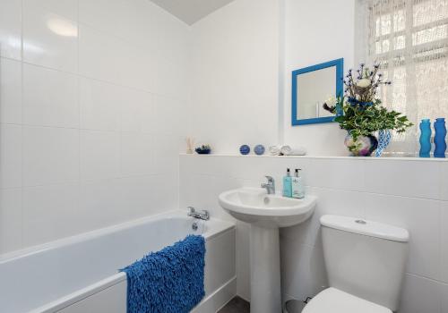 a white bathroom with a sink and a toilet and a tub at The Portsburgh Square Residence in Edinburgh