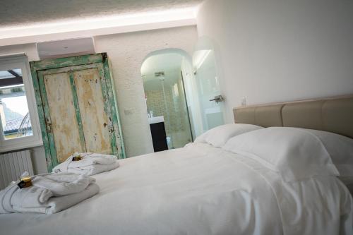 a bedroom with a bed with white sheets and a mirror at Rooftop Apartment in Garda