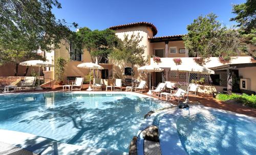 una grande piscina con sedie e ombrelloni di Hotel Colonna San Marco a Porto Rotondo