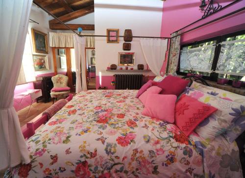 ein Schlafzimmer mit einem großen Bett mit rosa Kissen in der Unterkunft La Canonica dei Fiori - Anna Fendi Country House in Ronciglione