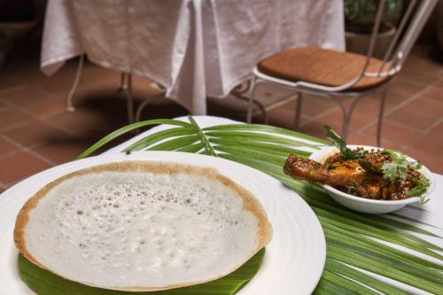 a table with a plate of food and a bowl of food at Maison Perumal Pondicherry - A CGH Earth Experience in Puducherry