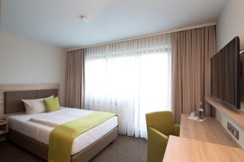 een hotelkamer met een bed en een televisie bij ARAMIS Tagungs- und Sporthotel in Gäufelden
