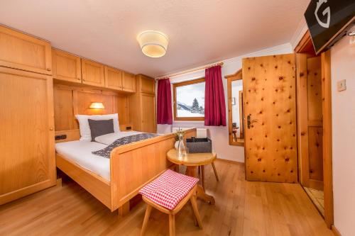 ein kleines Schlafzimmer mit einem Bett und einem Tisch in der Unterkunft Haus Gollas in Sankt Anton am Arlberg