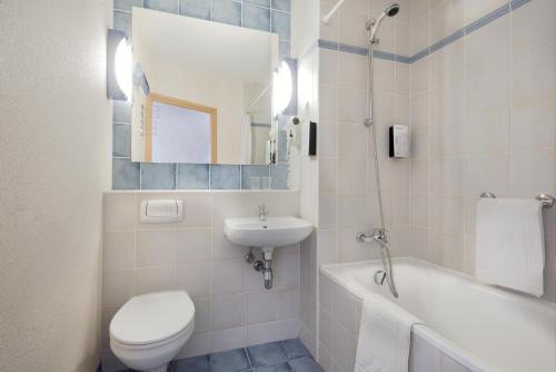 a bathroom with a toilet and a sink and a tub at Campanile Lublin in Lublin