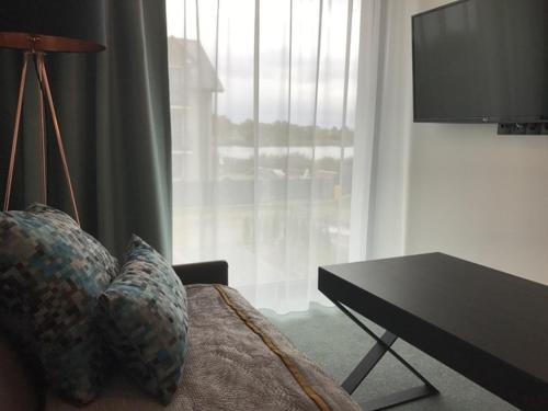 a room with a bed with a table and a television at Armada Holiday House in Dziwnów