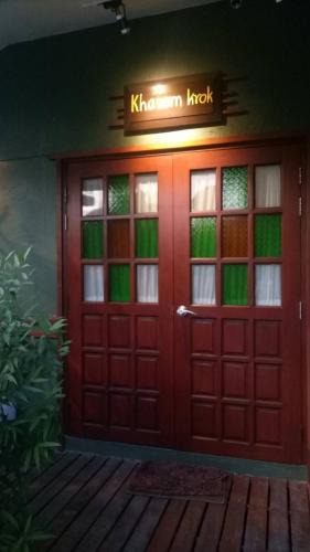 a red door with a sign that reads koren knock at Baan Jaru in Chiang Rai