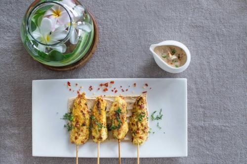 a white plate with skewers of food on a table at Palais De Mahe - A CGH Earth Experience in Puducherry