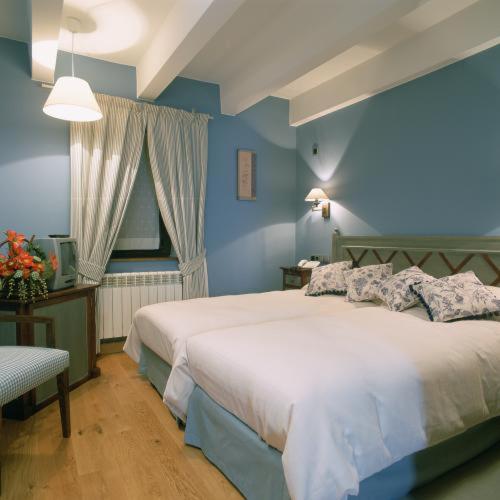 a blue bedroom with a bed and a window at Hotel Casa Estampa in Escuñau