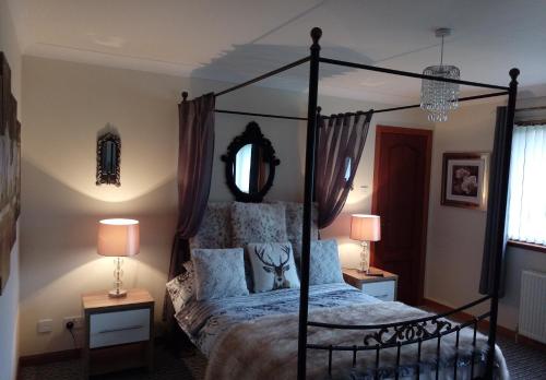 a bedroom with a canopy bed and two lamps at One Strathview B&B in Forfar
