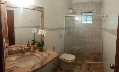 a bathroom with a sink and a toilet and a shower at Quartos Uberlandia in Uberlândia