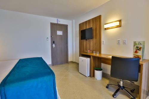 a room with a bed and a desk and a computer at ARCUS Hotel By Atlântica in Aracaju