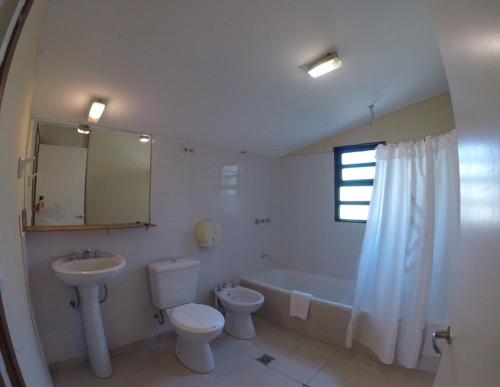 a bathroom with a sink and a toilet and a tub at Hostel Los Pioneros in El Calafate