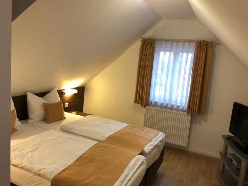a bedroom with a large bed and a television at Hotel Garni Goldene Traube in Bad Windsheim