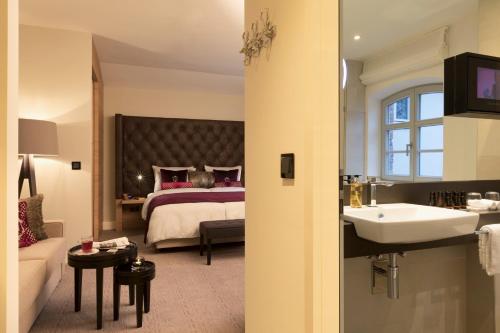 a bathroom with a bed and a sink in a room at Hotel Brunnenhaus Schloss Landau in Bad Arolsen