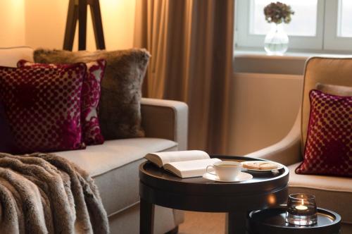 a living room with a couch and a table with a book at Hotel Brunnenhaus Schloss Landau in Bad Arolsen